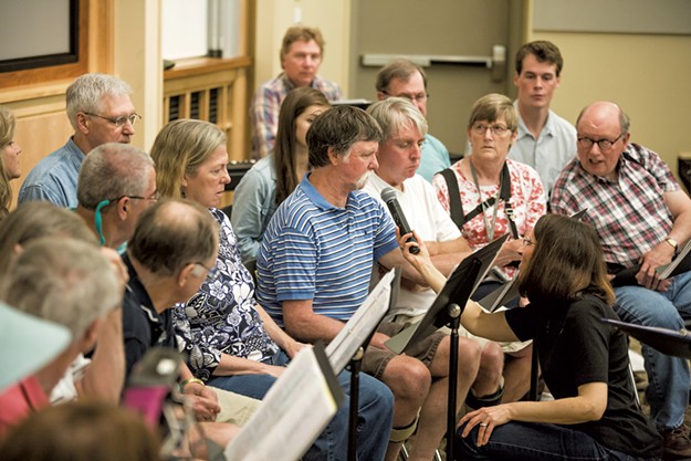 Image: Director Karen McFeeters Leary holding the microphone for Bob, a member of the choir, at a rehearsal.